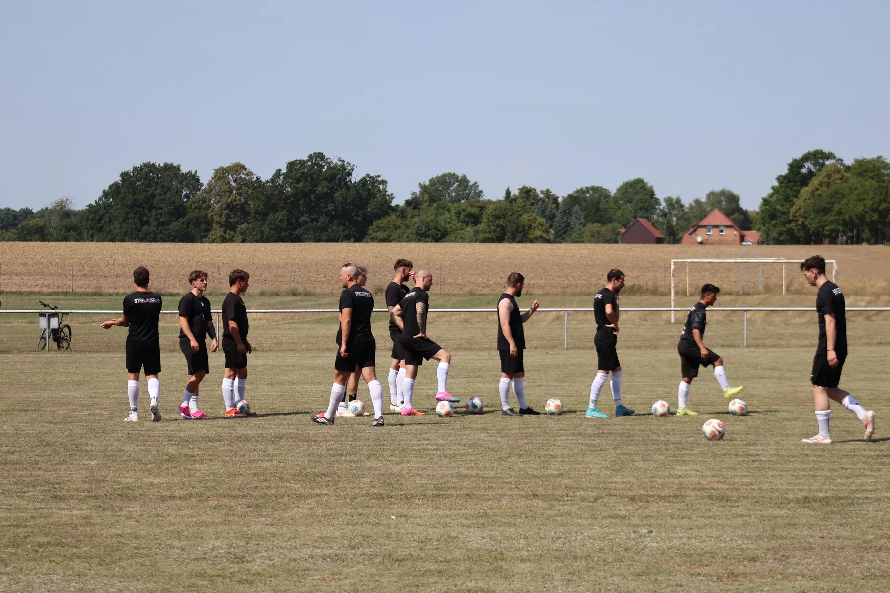 Spieler des Strelitzer FC beim Aufwärmen auf dem Platz, dahinter Felder und weiter Himmel